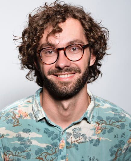 a smiling curly-haired guy on a hawaiian polo